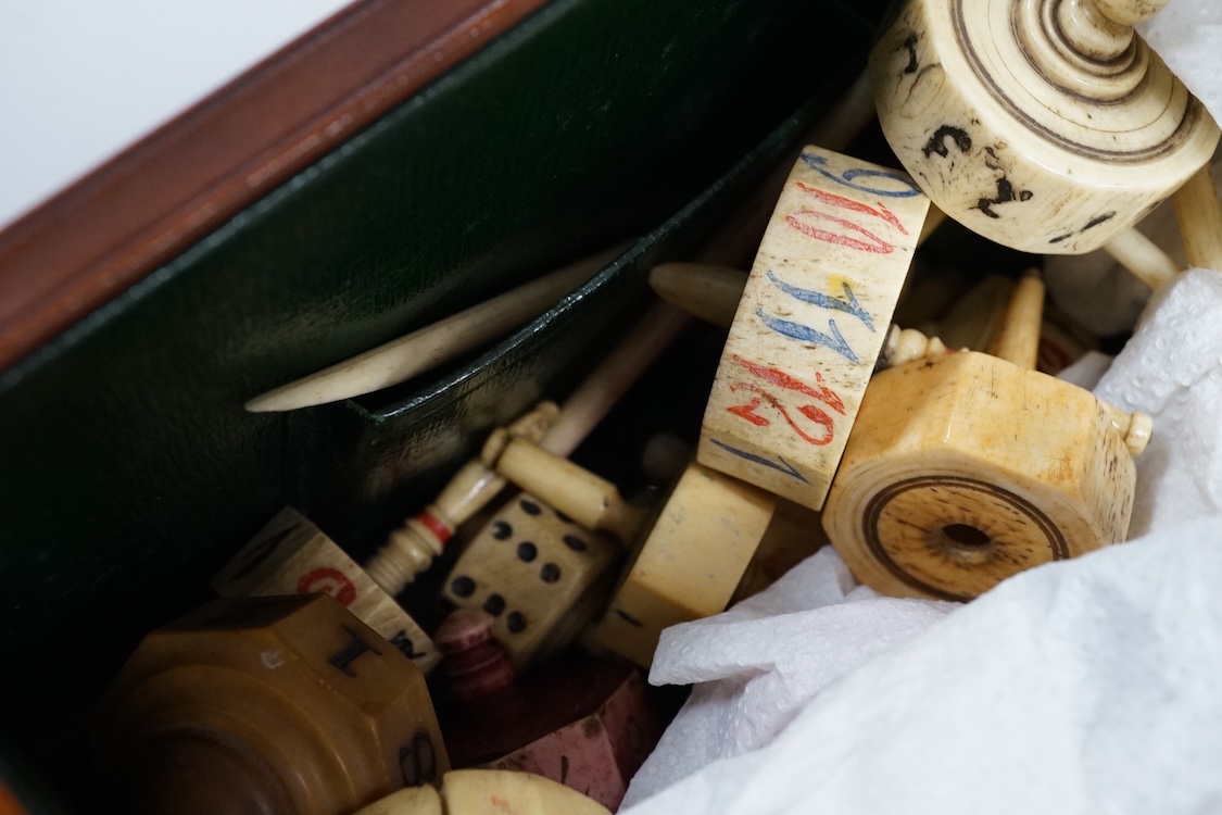 A collection of 19th century bone or coquille nut teetotum gaming spinners or twirlers and gaming items, in a leather box